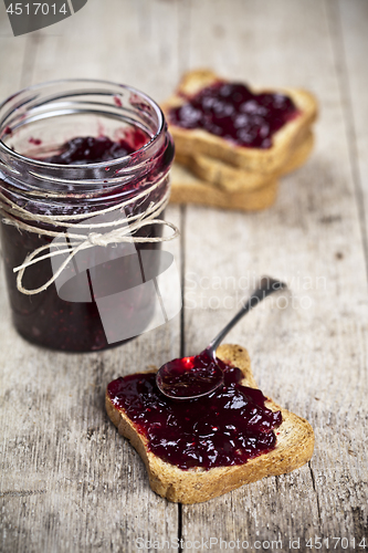 Image of Toasted cereal bread slices and jar with homemade wild berries j