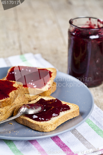 Image of Fresh toasted cereal bread slices with homemade cherry jam in ja
