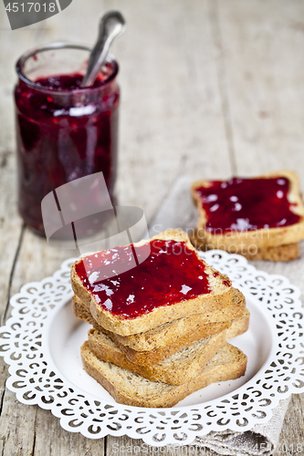 Image of Toasted cereal bread slices on white plate and jar with homemade