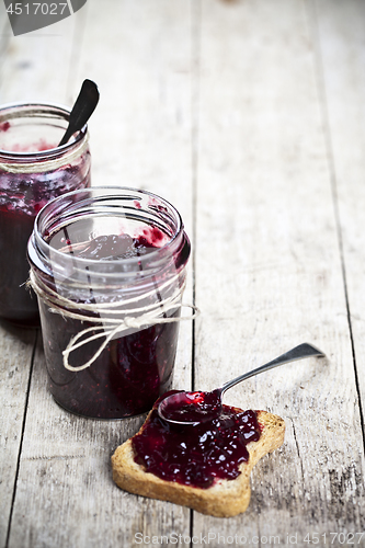 Image of Fresh cereal bread slices and jars with homemade wild berries  a