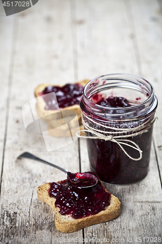 Image of Toasted cereal bread slices and jar with homemade wild berries j