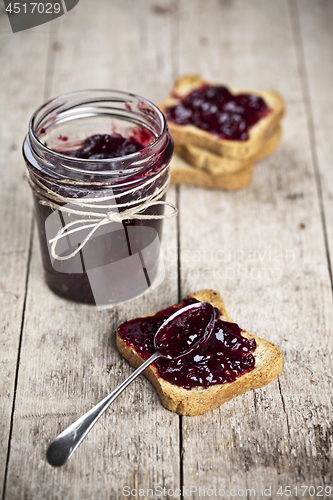Image of Toasted cereal bread slices and jar with homemade wild berries j