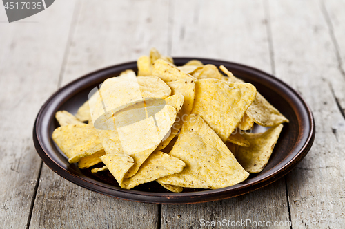 Image of Nachos chips on brown ceramic plate. 