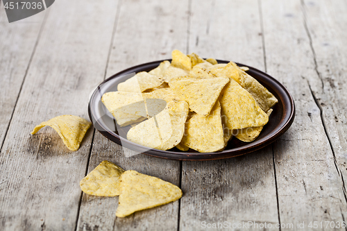 Image of Nachos chips on brown ceramic plate.