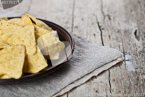 Image of Mexican nachos chips on brown ceramic plate on linen tablecloth.