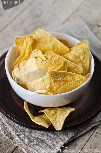 Image of Mexican nachos chips in white bowl on brown ceramic plate on lin