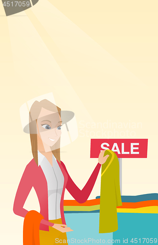 Image of Young woman choosing clothes in the shop on sale.