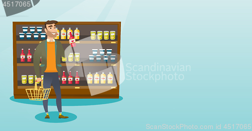 Image of Man holding shopping basket and bottle of sauce.