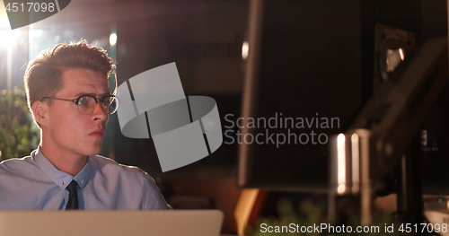 Image of man working on computer in dark office