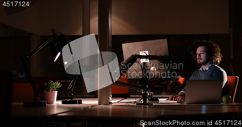 Image of man working on computer in dark office