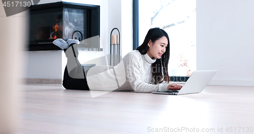 Image of Asian woman using laptop on floor