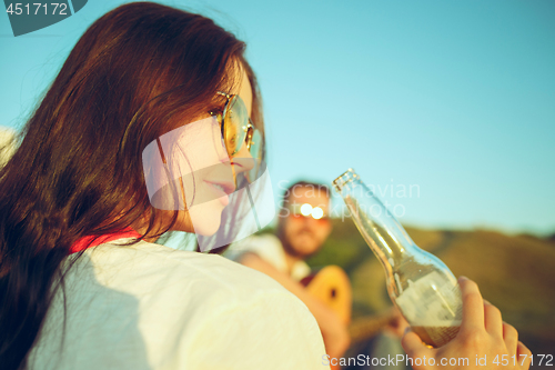 Image of Couple sitting and resting on the beach playing guitar on a summer day near river