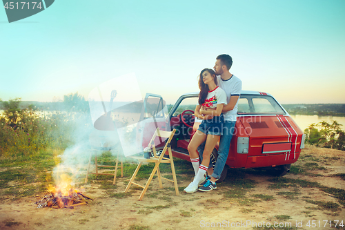 Image of Couple sitting and resting on the beach playing guitar on a summer day near river