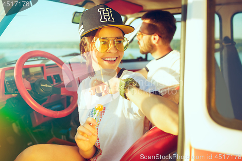 Image of Laughing romantic couple sitting in car while out on a road trip at summer day