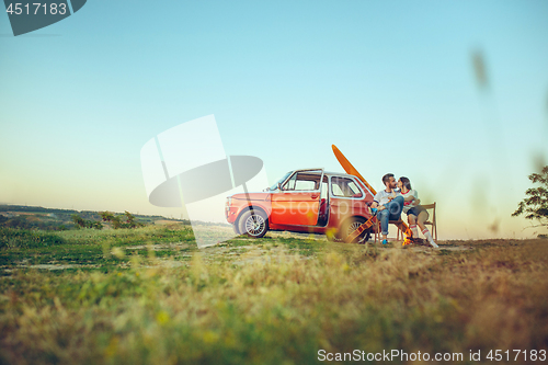 Image of Couple sitting and resting on the beach playing guitar on a summer day near river