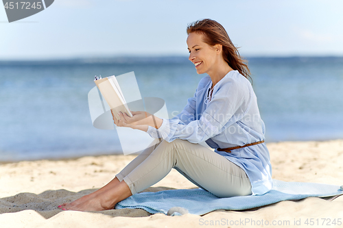 Image of happy smiling woman reading book on summer beach