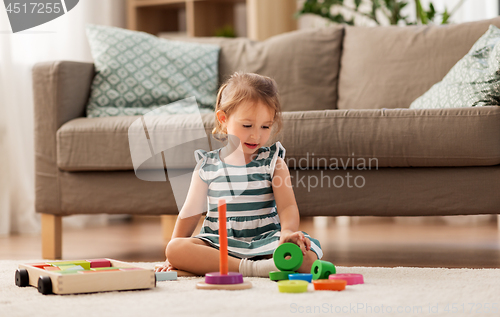 Image of happy baby girl playing with toy blocks at home