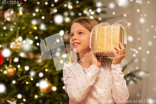 Image of smiling girl with christmas gift at home