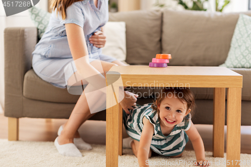 Image of pregnant mother and daughter playing at home