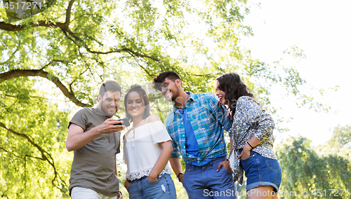 Image of smiling friends with smartphone in summer park