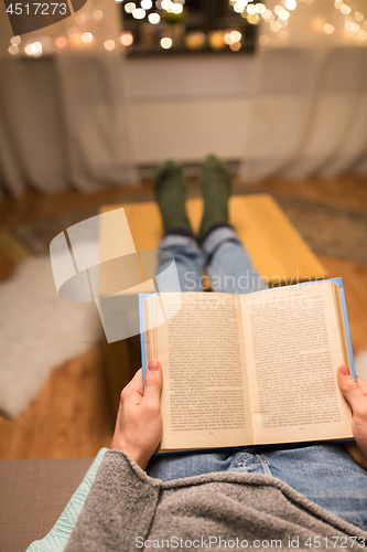 Image of close up of young man reading book at home