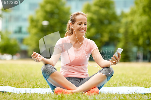 Image of woman listening to music on smartphone at park