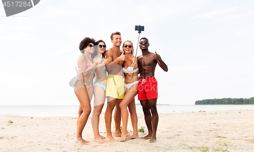 Image of friends taking selfie on beach and show thumbs up