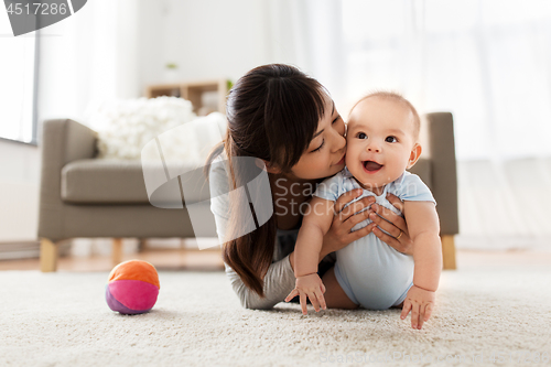 Image of happy young mother kissing little baby at home