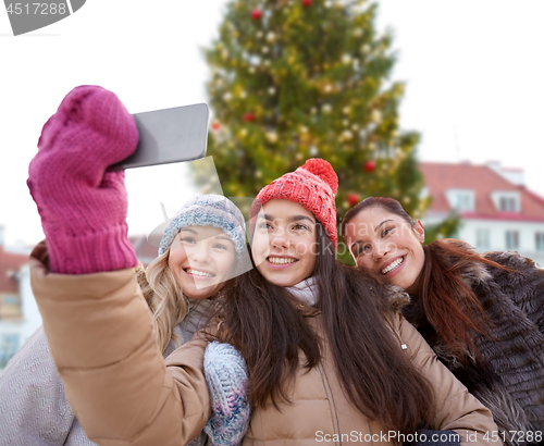 Image of teenage girls taking selfie over christmas tree