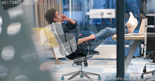 Image of businessman sitting with legs on desk