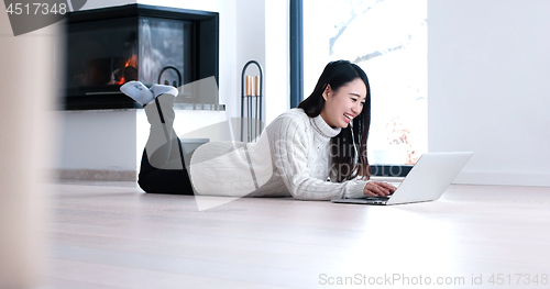 Image of Asian woman using laptop on floor