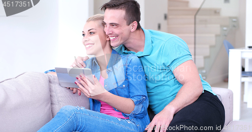 Image of couple relaxing at  home with tablet computers