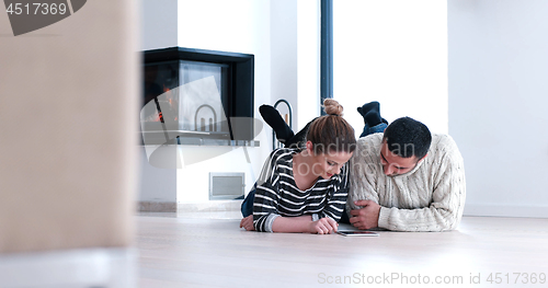 Image of Young Couple using digital tablet on the floor