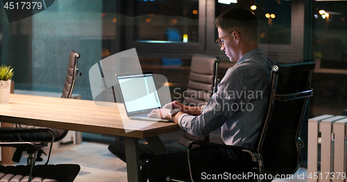 Image of man working on laptop in dark office