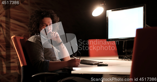 Image of man working on computer in dark office