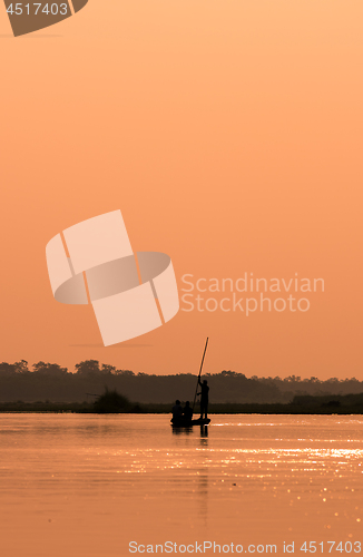 Image of Men in a boat on a river silhouette