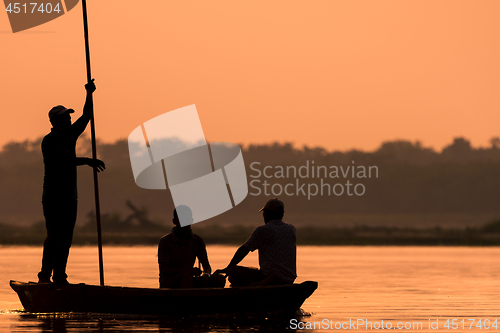 Image of Men in a boat on a river silhouette