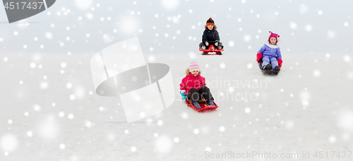 Image of kids sliding on sleds down snow hill in winter