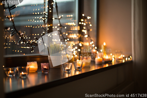 Image of candles burning on window sill with garland lights