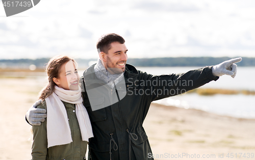 Image of smiling couple hugging on autumn beach