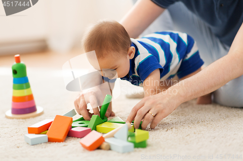 Image of baby boy and father playing with toys at home