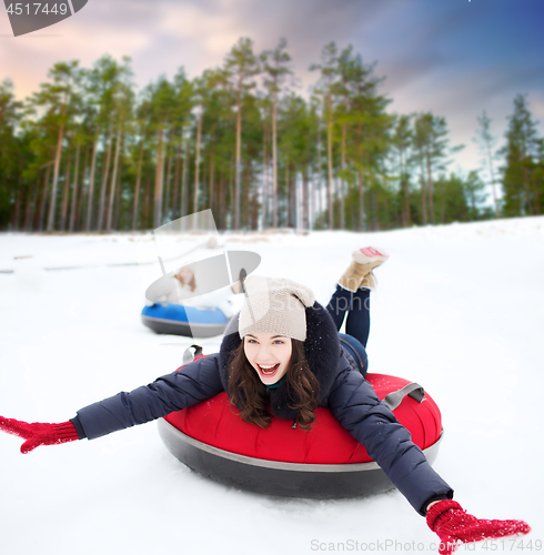 Image of happy teenage girl sliding down hill on snow tube