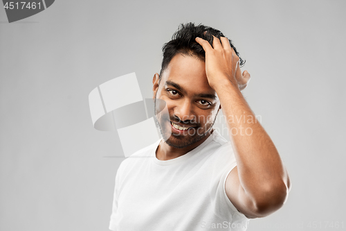 Image of indian man touching his hair over gray background