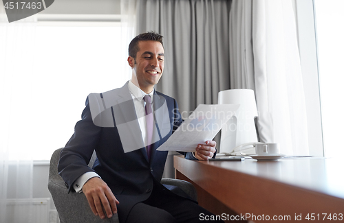 Image of businessman with papers working at hotel room