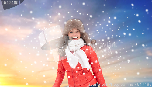Image of happy woman in winter fur hat over sky and snow