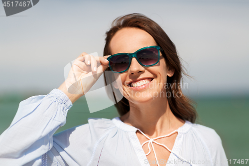 Image of happy smiling woman in sunglasses on summer beach