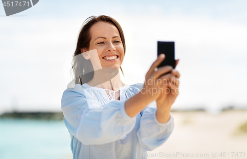 Image of happy smiling woman taking selfie on summer beach