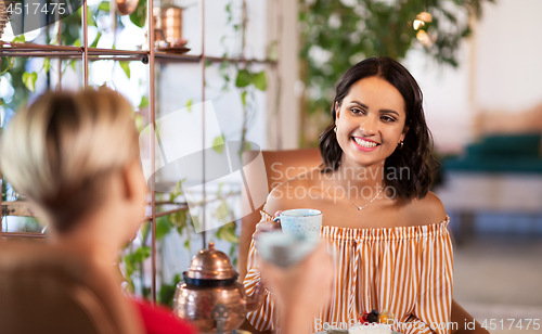 Image of female friends drinking coffee and talking at cafe