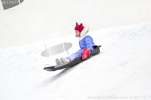 Image of happy little girl sliding down on sled in winter