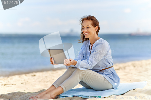 Image of happy smiling woman with tablet pc on summer beach